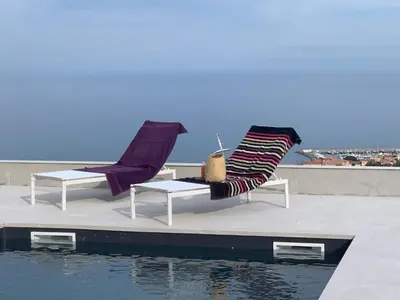 two chairs sitting on a ledge next to the water at Villa Mare d'argentu La solenzara in Sari Solenzara