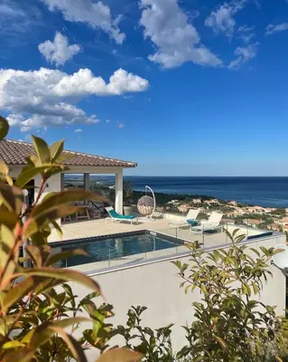 a swimming pool with chairs and the ocean in the background at Villa Mare d'argentu La solenzara in Sari Solenzara