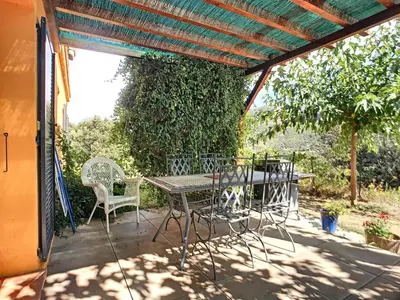 a patio with a table and chairs under a pergola at U mè sognu in Arbellara