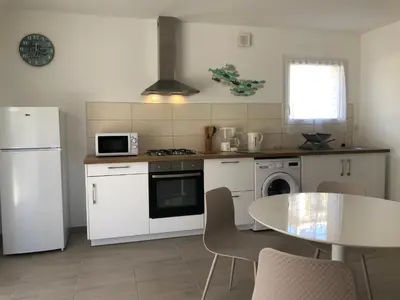 a kitchen with white appliances and a table with chairs at U SOLE in Ajaccio
