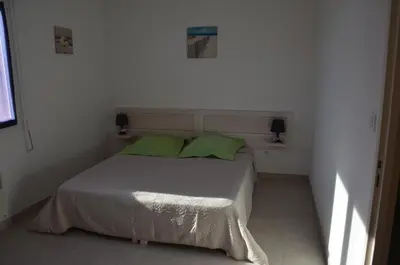 a white bedroom with a bed with two green pillows at Villa Fior 50 in Santa-Maria-Poggio