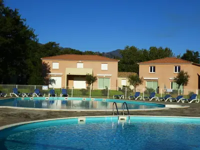 a swimming pool with chairs in front of a house at Villa Fior 50 in Santa-Maria-Poggio