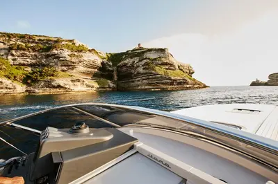a boat in the water next to some cliffs at Domaine & Villas Version Maquis in Bonifacio