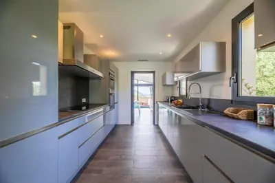 a kitchen with white cabinets and a tile floor at Domaine & Villas Version Maquis in Bonifacio