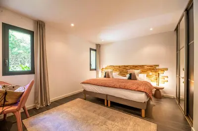a bedroom with a bed and a chair and a window at Domaine & Villas Version Maquis in Bonifacio