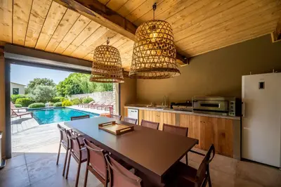 a kitchen with a table and chairs and a pool at Domaine & Villas Version Maquis in Bonifacio