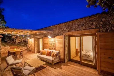 a wooden deck with a couch and a bed at Domaine & Villas Version Maquis in Bonifacio