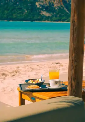 a table with a tray of food and a drink on the beach at Costa Nera Beach House in Porto-Vecchio
