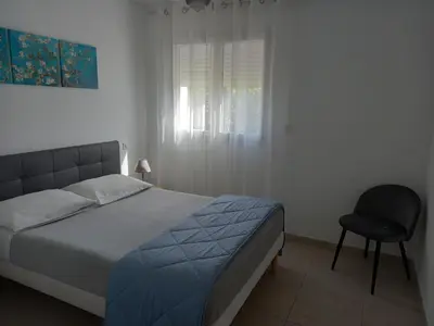 a bedroom with a bed and a chair and a window at U MANDARINU in Ajaccio