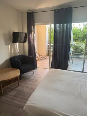 a bedroom with a bed and a chair and a balcony at Appartements PORTICCIO CENTRE in Porticcio