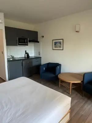 a room with a bed and two chairs and a table at Appartements PORTICCIO CENTRE in Porticcio