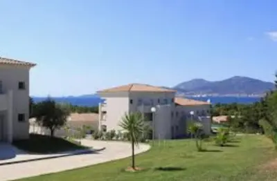 a building with a palm tree in the grass at Appartements PORTICCIO CENTRE in Porticcio