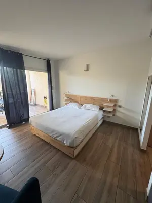 a bedroom with a large bed and a wooden floor at Appartements PORTICCIO CENTRE in Porticcio