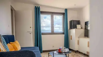 a living room with a blue couch and a window at Casa Nova Maison d'hôtes in Sagone