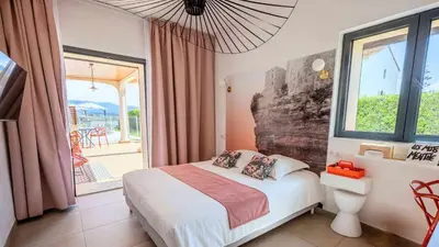 a bedroom with a bed and a large window at Casa Nova Maison d'hôtes in Sagone