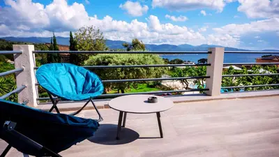 a table and chair on a balcony with a view of the water at Casa Nova Maison d'hôtes in Sagone