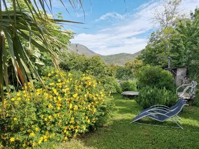 a garden with a bench and yellow flowers and a bush at Chambre d'hôtes couvent d'Alando in Alando