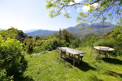 two picnic tables in a field with mountains in the background at Chambre d'hôtes couvent d'Alando in Alando