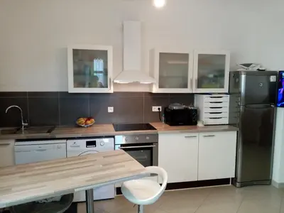 a kitchen with white cabinets and a black refrigerator at Appartement cours Bonaparte in Sartène