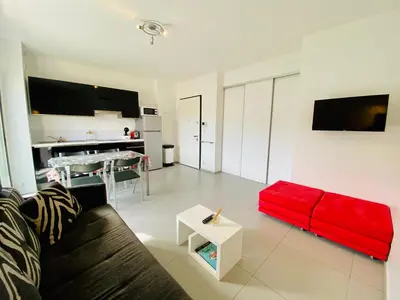 a living room with a red couch and a table at Studio tout confort en centre ville in Propriano