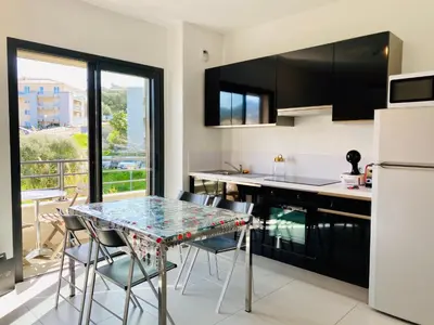 a kitchen with a table and chairs and a refrigerator at Studio tout confort en centre ville in Propriano