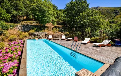 a swimming pool with a wooden deck and flowers at Awesome Home In Ville-Di-Paraso in Ville-di-Paraso