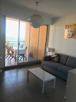 a living room with a couch and a table at T2 route des sanguinaires vue mer panoramique in Ajaccio
