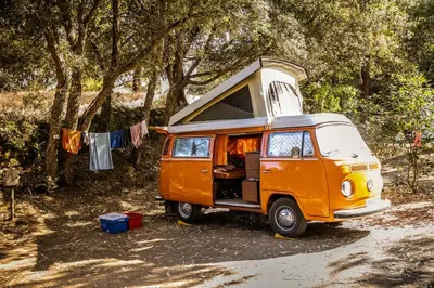 an orange and white van parked next to trees at Camping Olva - Maeva in Sartène