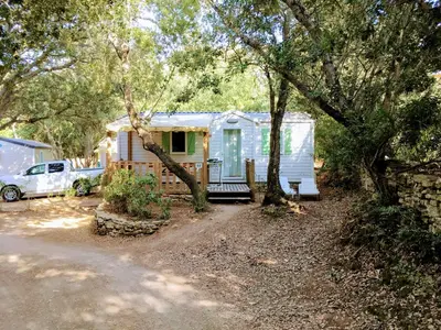 a tiny house with a porch in the woods at Camping Campo Di Liccia - Maeva in Bonifacio