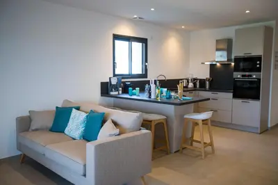 a living room with a couch and a kitchen at Résidence Saint Cyprien plage in Porto-Vecchio