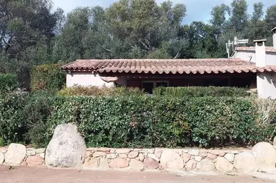 a house with a stone wall in front of a building at casa-anghjulina in Porto-Vecchio