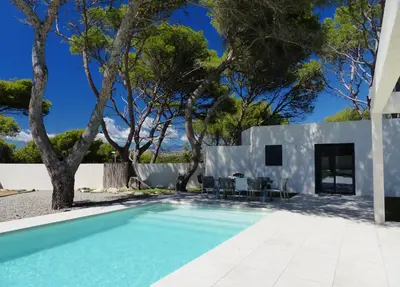 a swimming pool in front of a house with trees at Villa Laricio in Bonifacio