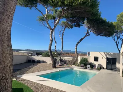 a swimming pool in front of a house with trees at Villa Laricio in Bonifacio