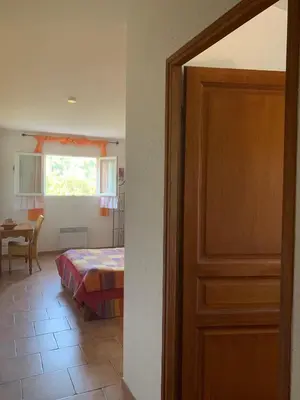 a door to a bedroom with a bed and a table at l'Ogliastru in Ucciani