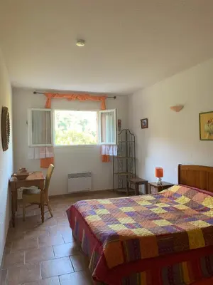 a bedroom with a bed and a table and a window at l'Ogliastru in Ucciani