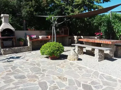 a stone patio with a bench and a fireplace at Magnifique villa piscine Propriano in Olmeto