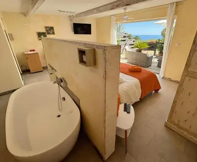 a bathroom with a tub and a bed with a window at Fiore di Machja in Coti-Chiavari