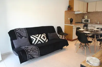 a living room with a black couch and a kitchen at Paomia in Cargèse