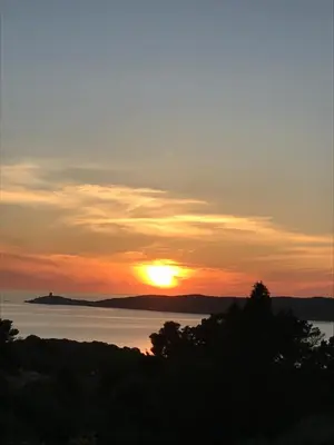 a sunset over the water with the sun in the sky at Paomia in Cargèse