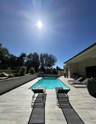 a swimming pool with lounge chairs next to a building at VILLA BENOA in Oletta