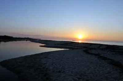 a sunset on the shore of a body of water at Franceschini in Ghisonaccia
