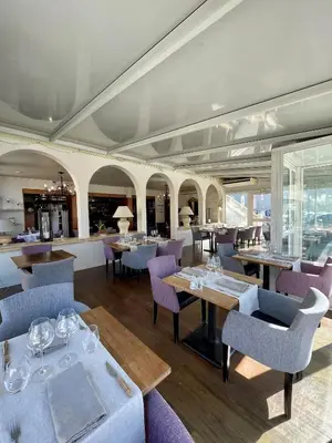 a restaurant with purple chairs and tables and windows at Franceschini in Ghisonaccia