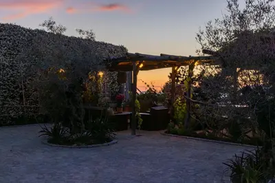 a garden at sunset with a pergola at Villa Kirssis in Porticcio