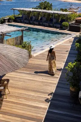 a woman walking on a wooden deck next to a swimming pool at Villa Kirssis in Porticcio