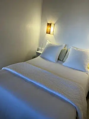 a bedroom with a large white bed with a light on it at Résidence Colombara in Cargèse