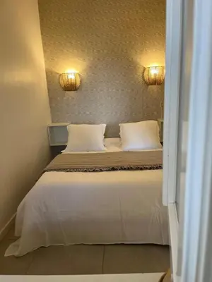 a bedroom with a bed with two pillows and two lights at Résidence Colombara in Cargèse