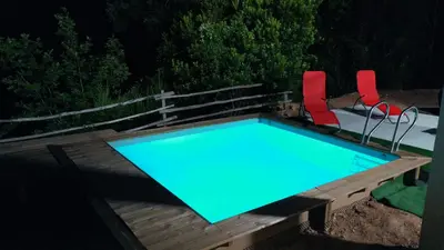 a swimming pool with two red chairs next to it at Corse et Zen VILLA SUR LES BOIS 85m2 5à7 pers in Taglio-Isolaccio