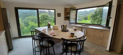 a kitchen with a table with four chairs and large windows at Corse et Zen LOFT ZEN 145m2 8à9 pers in Taglio-Isolaccio