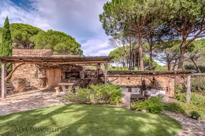 a stone house with a garden and a wooden pergola at Villa Serenita Pallombaggia in Porto-Vecchio