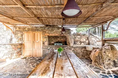 a wooden table in a room with a stone wall at Villa Serenita Pallombaggia in Porto-Vecchio